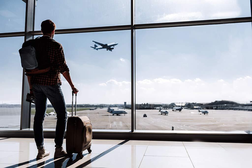 Man standing in airport watching jet taking off